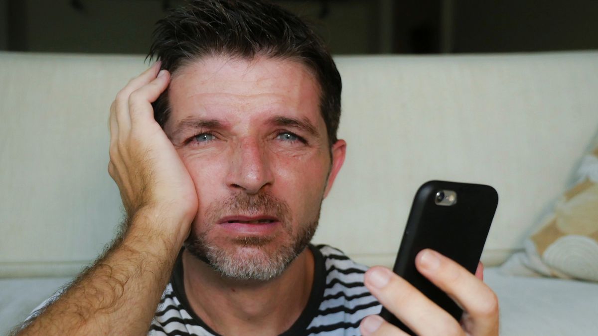 man looking at his phone tired