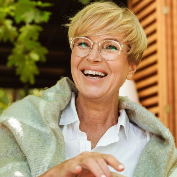 senior woman smiling outside with a book