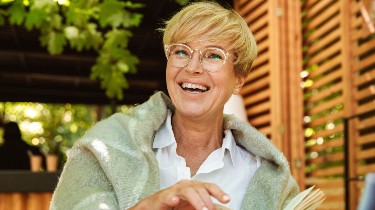 senior woman smiling outside with a book