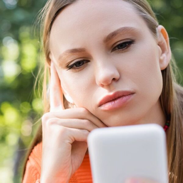 woman staring at her phone in the park