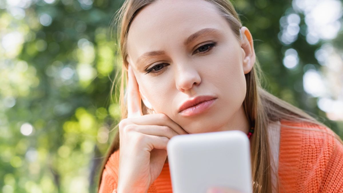 woman staring at her phone in the park