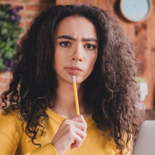 woman with curly hair thinking with pencil