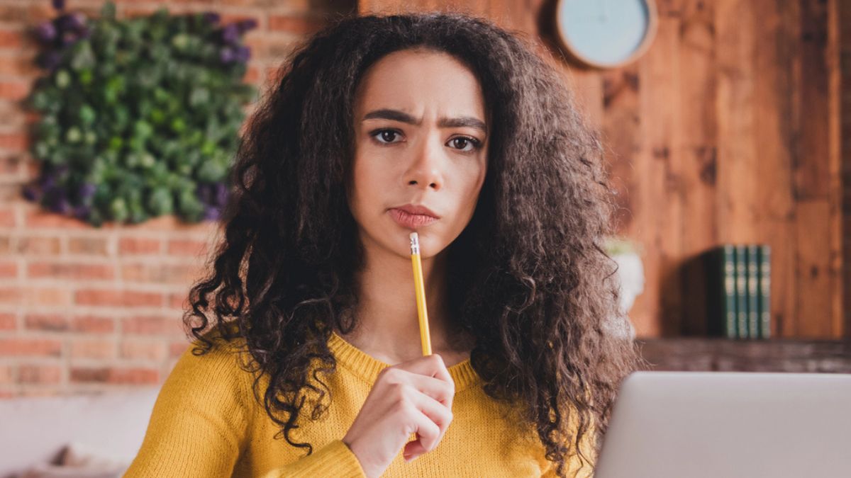 woman with curly hair thinking with pencil