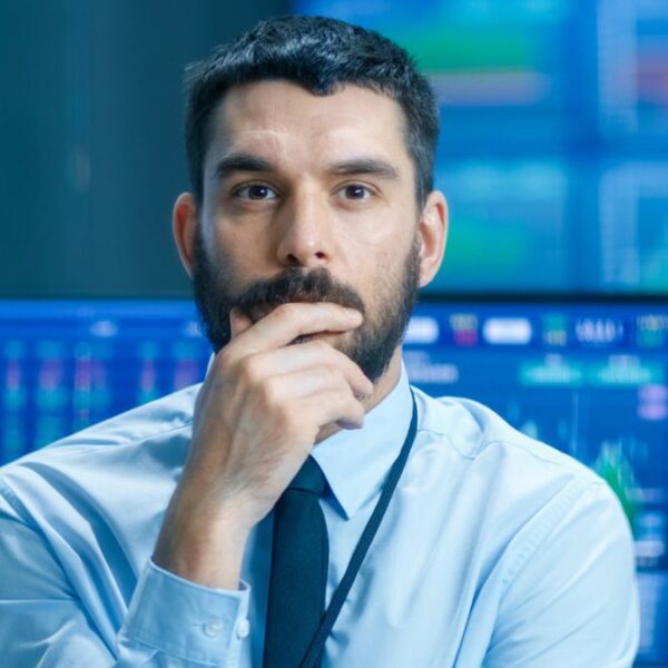 man standing in front of stock market computer