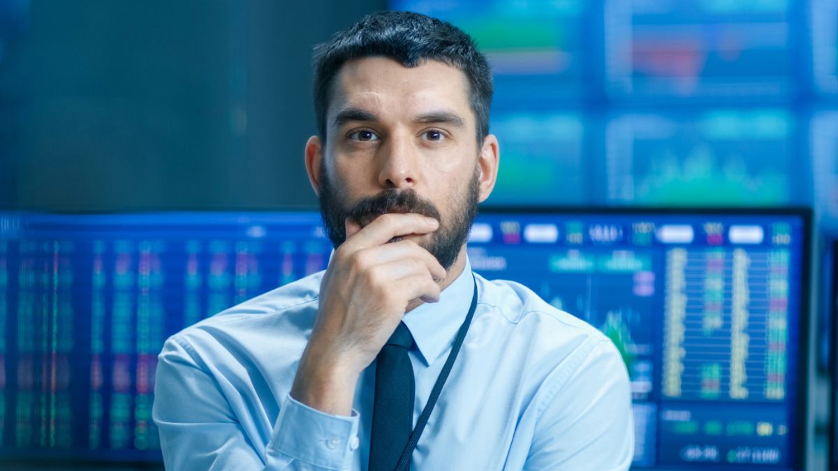 man standing in front of stock market computer