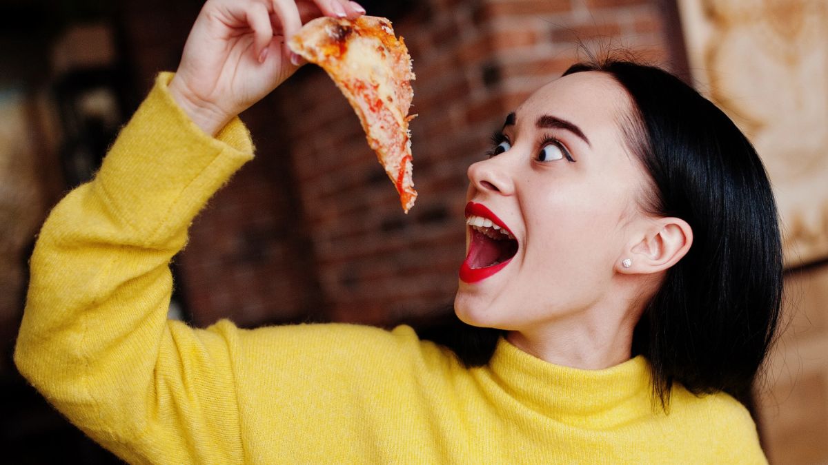 woman eating pizza at restaurant