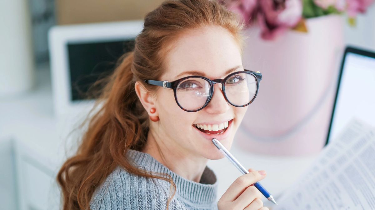 woman smiling with glasses laptop pen