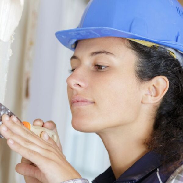 woman with hard hat doing dry wall