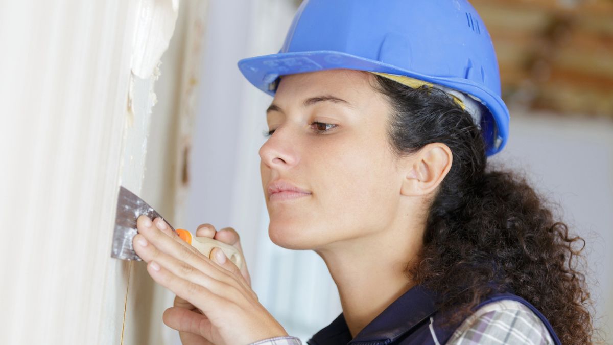 woman with hard hat doing dry wall