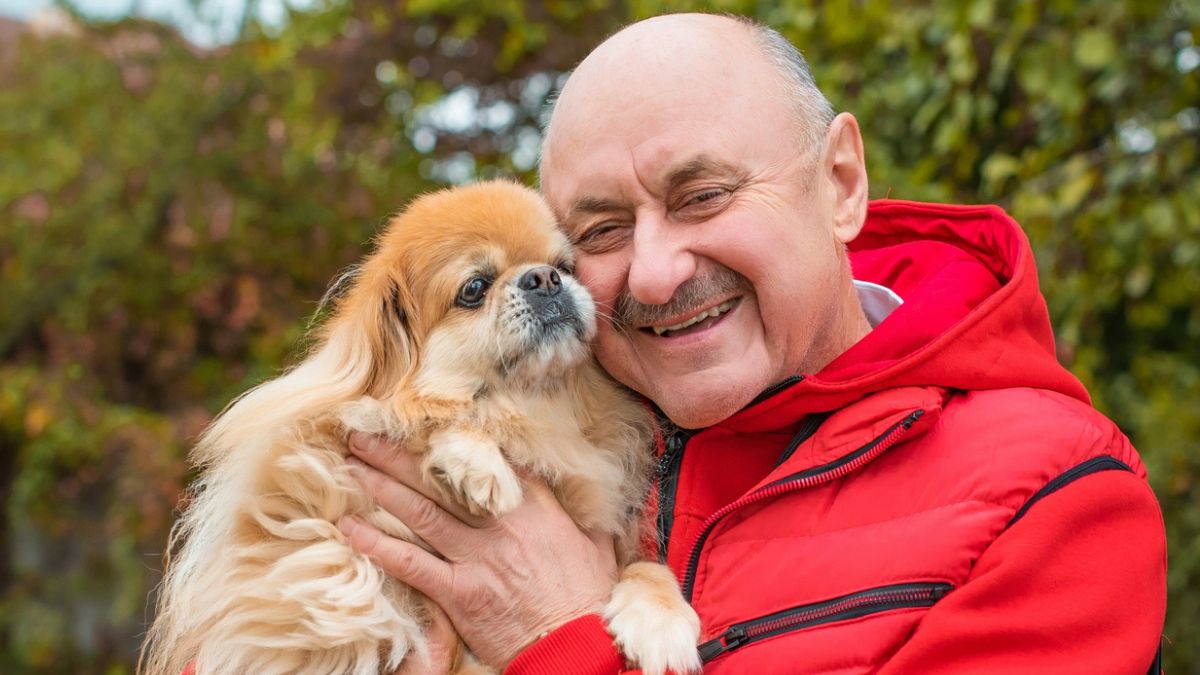 man red jacket hugging dog