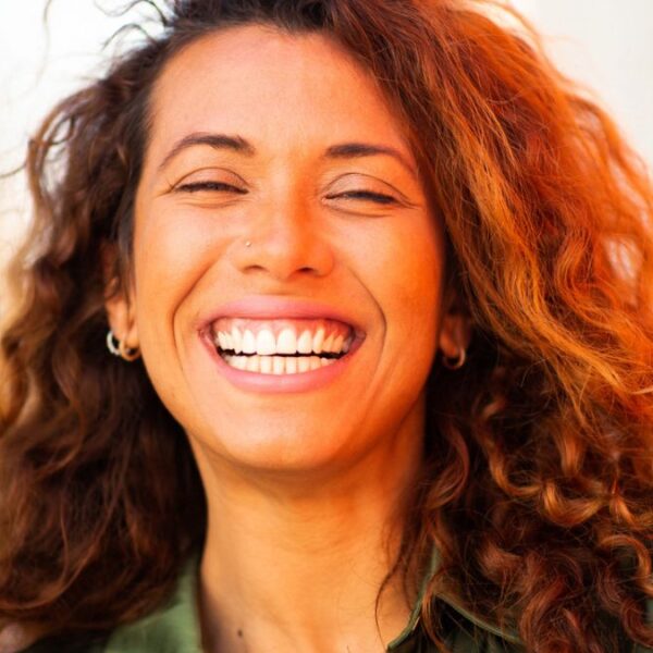 woman with curls smiling outside