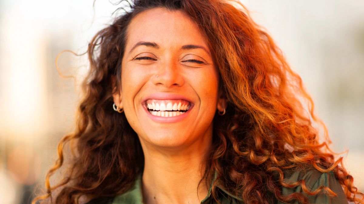 woman with curls smiling outside